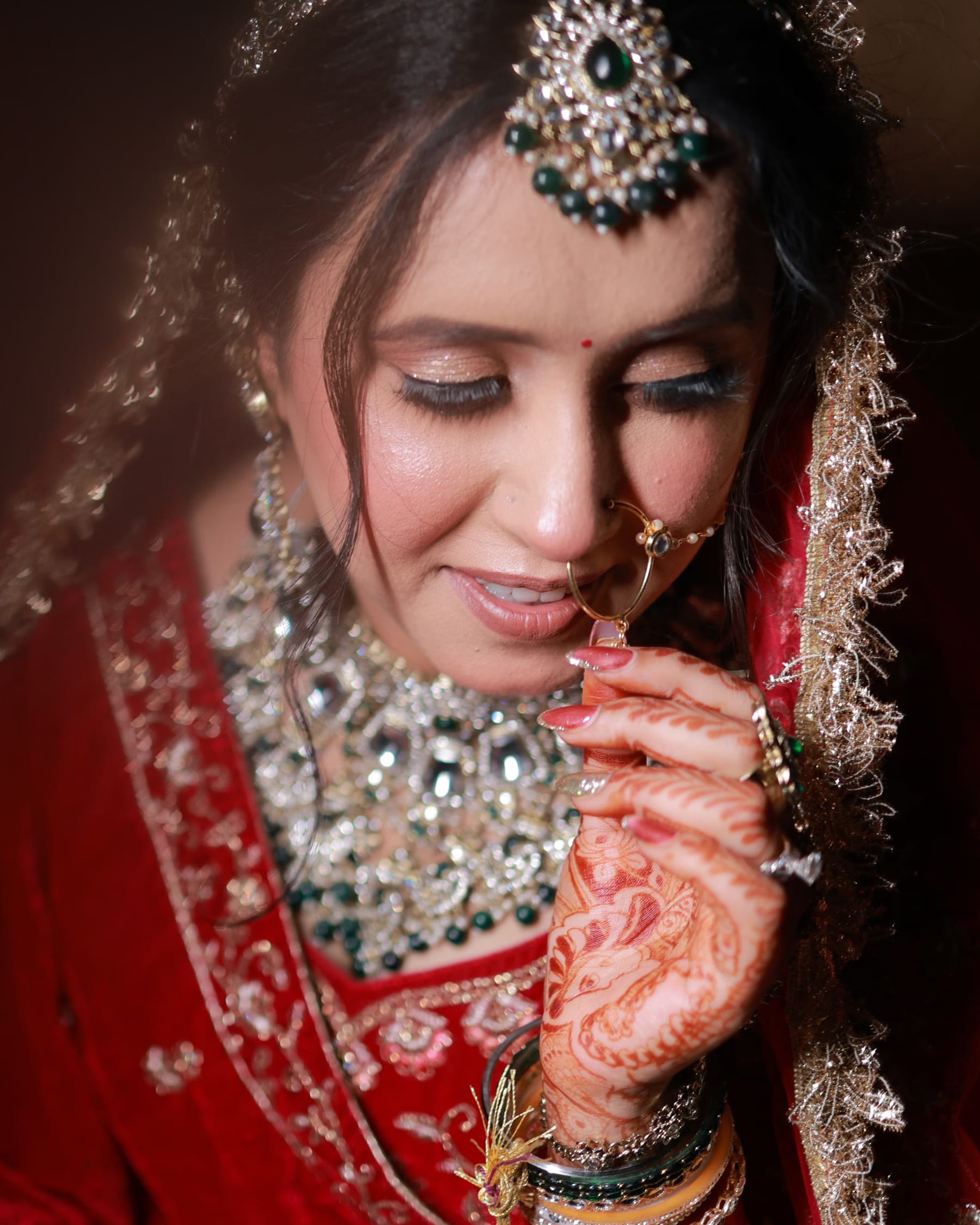 Bride seated in the salon chair, dupatta being pinned, soft window light
